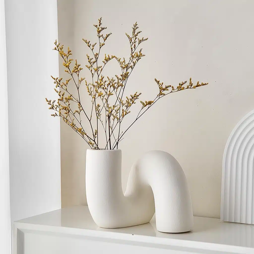 a white vase with yellow flowers in it