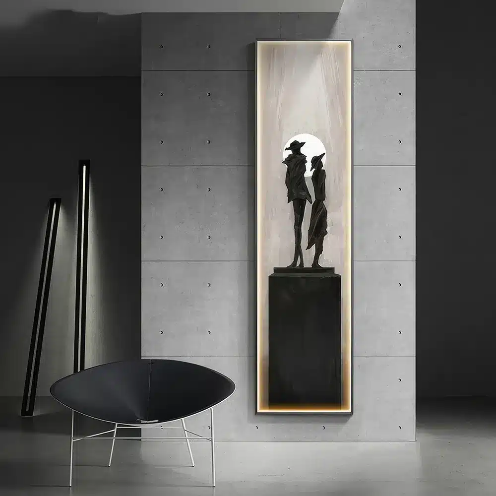 A modern, minimalistic interior featuring a tall, narrow painting of two silhouetted figures on a pedestal. The room has a grey color scheme with a sleek black chair and geometric lighting in the background.