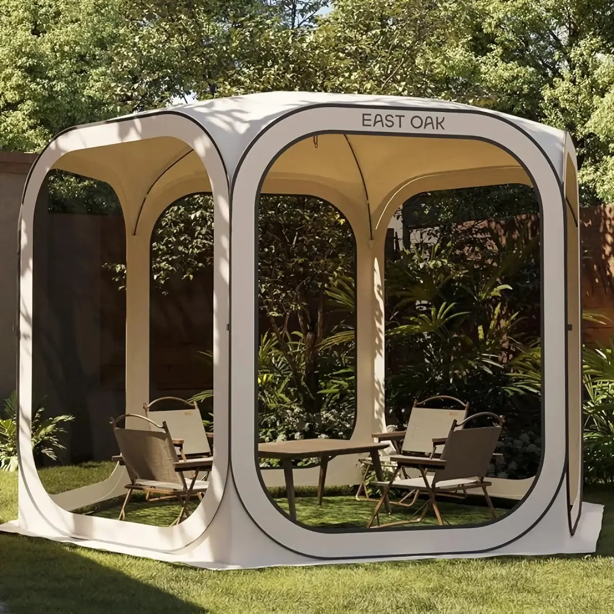 A modern outdoor gazebo labeled East Oak, featuring a cube-like design with arching openings. Inside are several chairs and a table on a grassy lawn, surrounded by lush trees and plants.